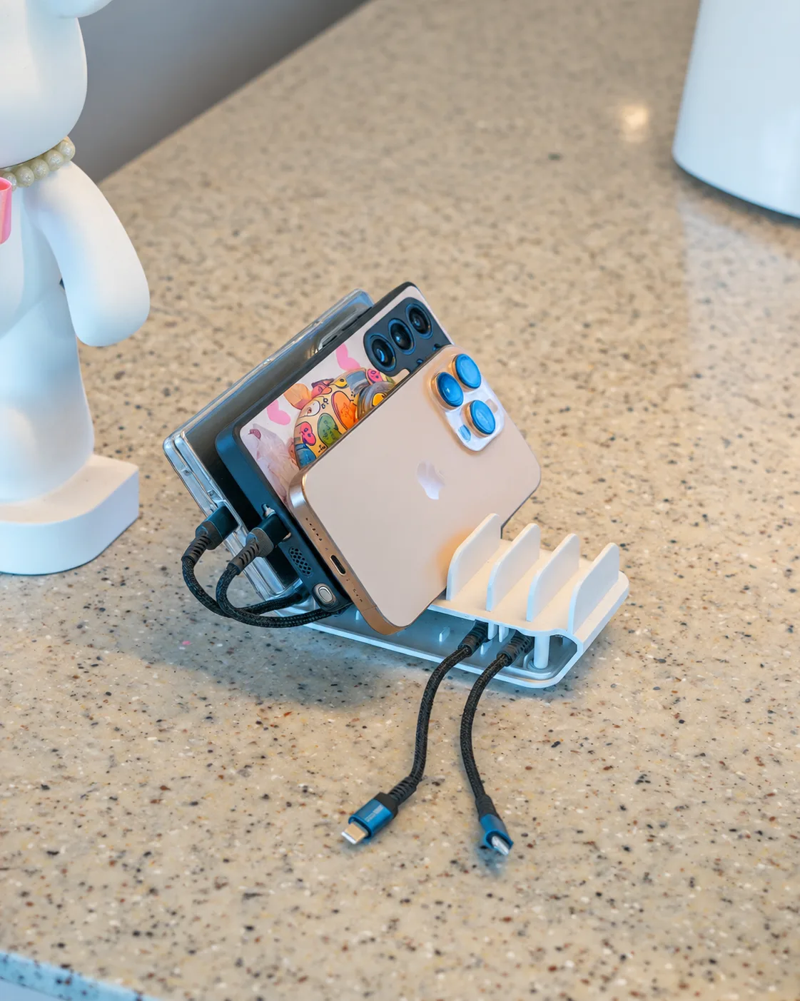 Phones upright in Badadang's charging stand, with Lightning (8-pin) and USB-C cables